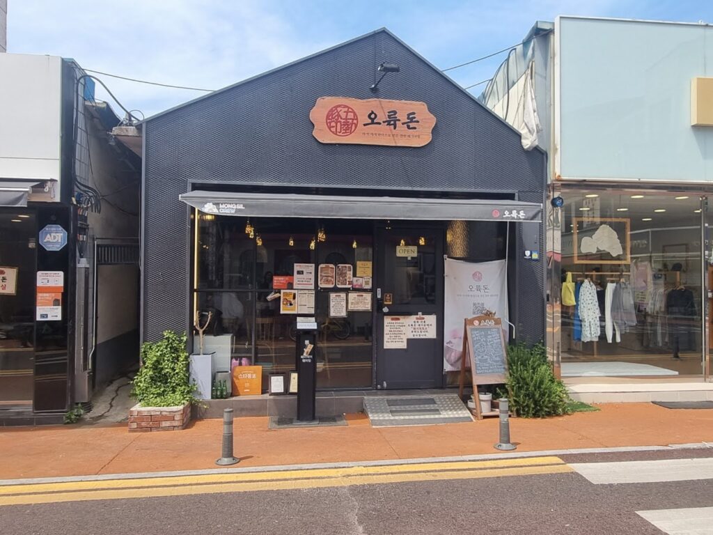 Front of Orokdon Korean restaurant with dark exterior and glass doors, located between a cafe and a clothing store.